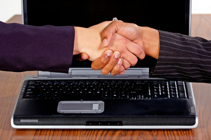 Image of hands shaking over laptop computer