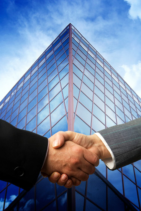 Image of 2 hands shaking in front of skyscraper