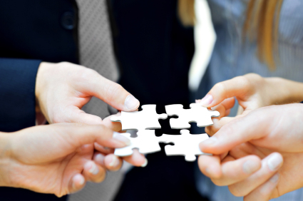 Image of 4 hands holding interconnecting puzzle pieces