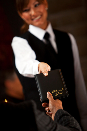 Image of waitress taking billing folder from customer